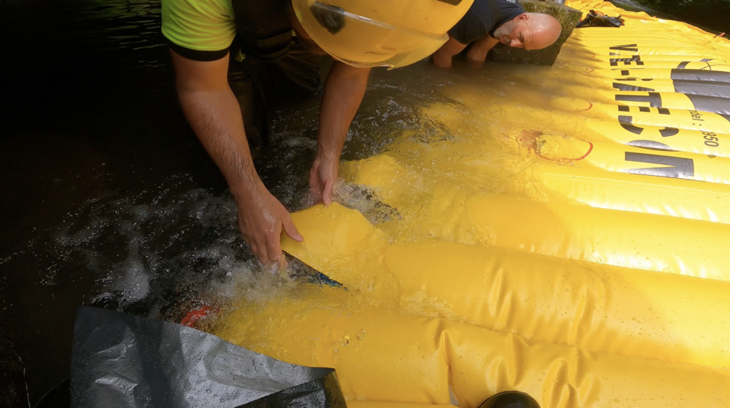 Techniciens ajustant les trous de relâche d’un batardeau souple Water-Gate© pour contrôler le débit dans la rivière Valmont à Fécamp.